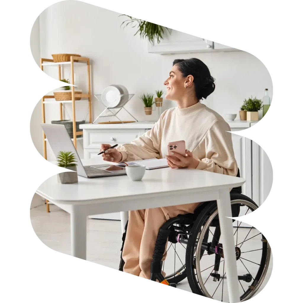 Happy woman in wheelchair at home sitting at desk with laptop