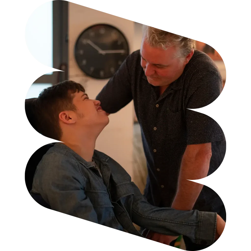 Disabled boy looking up at support worker, smiling
