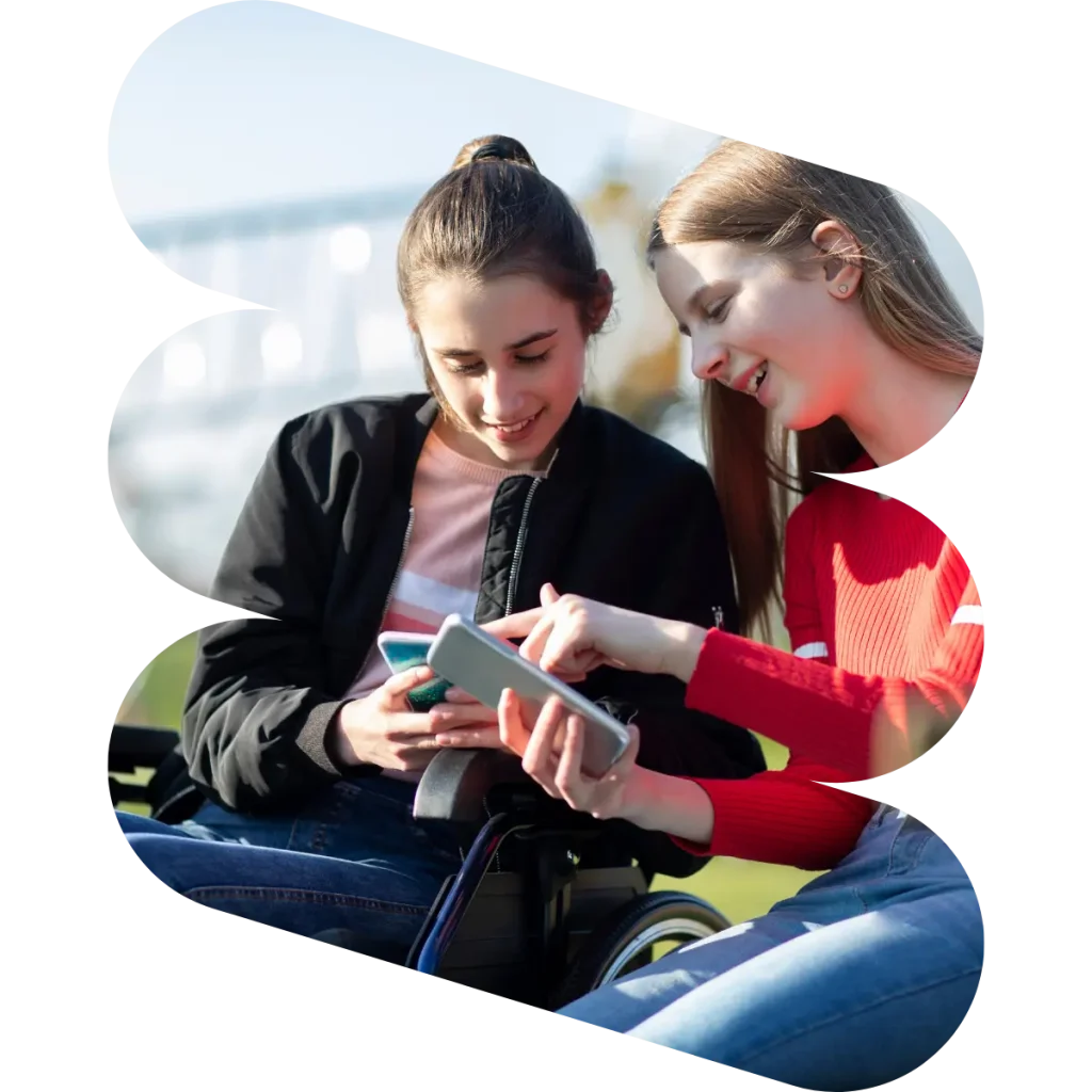 Two disabled friends in wheelchairs smiling and looking at mobile phones