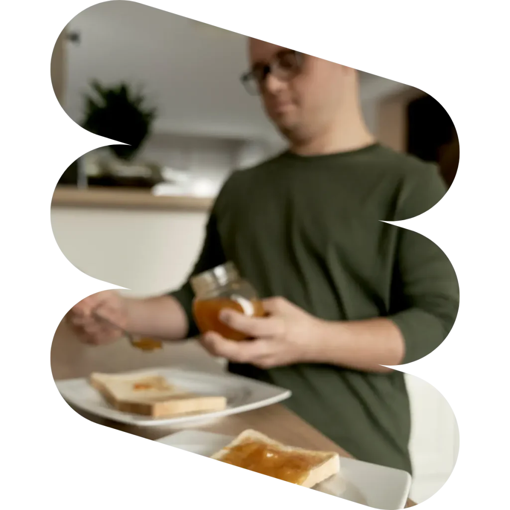Disabled man with down syndrome making marmalade toast at home in kitchen